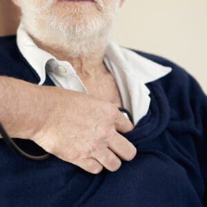 Hand holding stethoscope against patient’s chest.