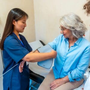 Nurse taking blood pressure of elderly patient.