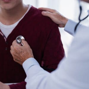 Doctor using stethoscope on patient in consultation.